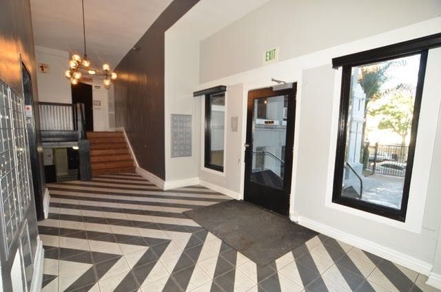 Hallway with patterned floor, mailboxes, doors, stairs, and exit sign.