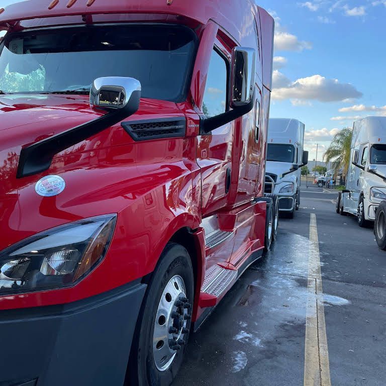 a red semi truck is parked in a parking lot