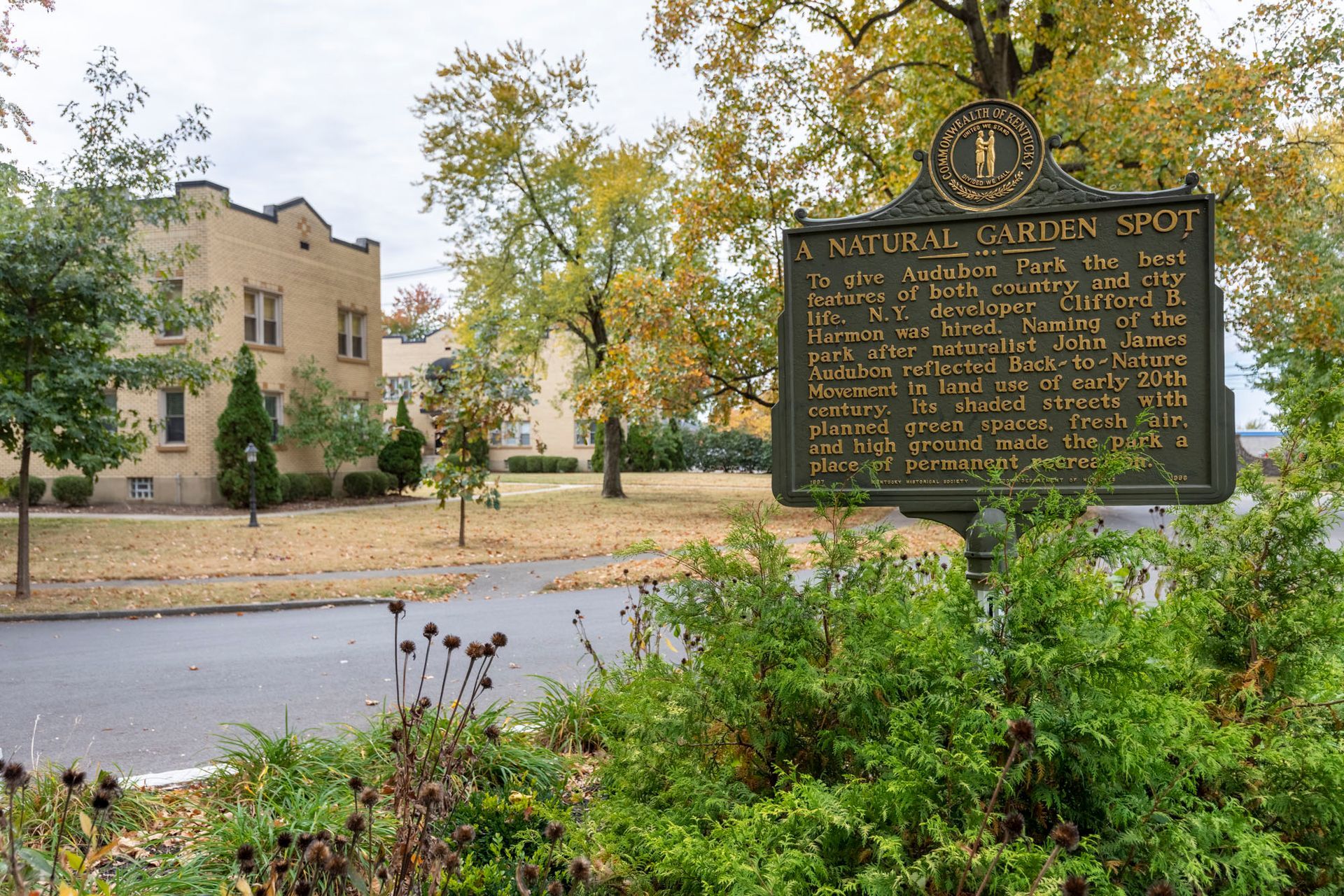 A historical marker in a park with a building in the background