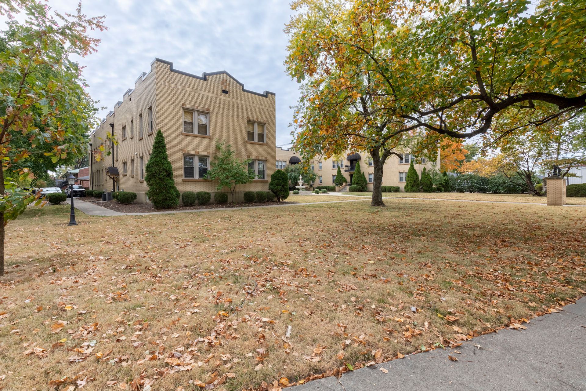 A large building with a lot of leaves on the ground in front of it