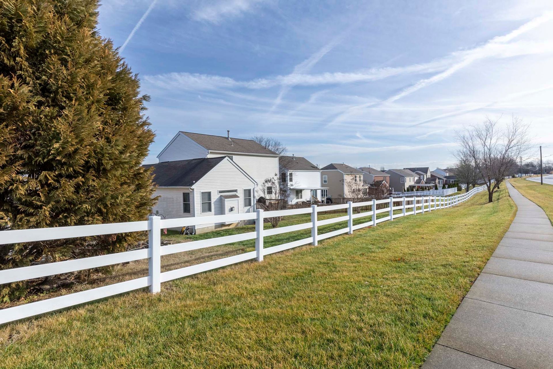 a white fence along a sidewalk in front of a row of houses .