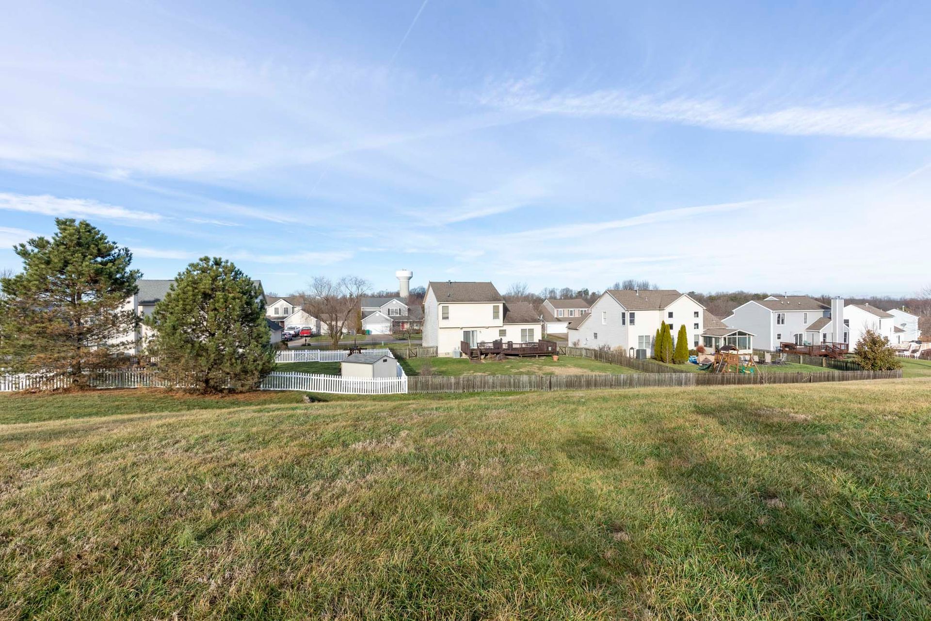 there is a large grassy field in the middle of a residential area with houses in the background .