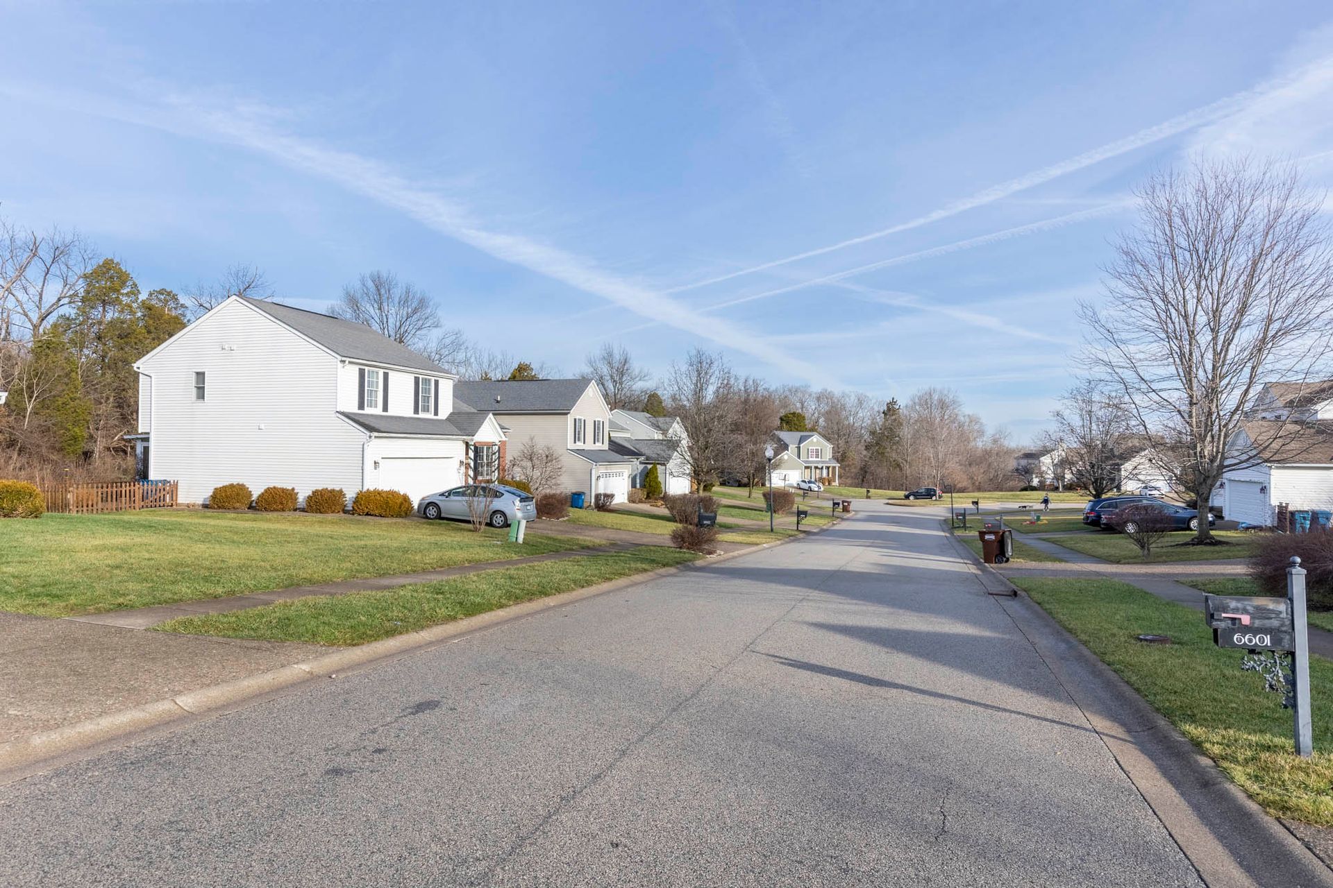 a street in a residential neighborhood with a lot of houses and cars parked on the side of the road .