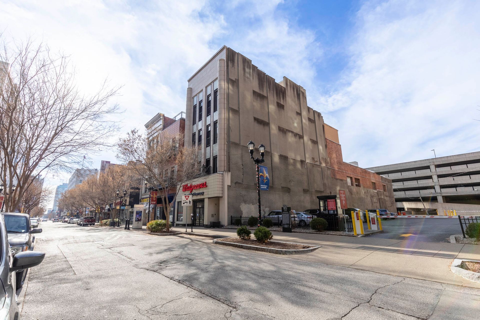 a large building is sitting on the corner of a city street next to a parking garage .