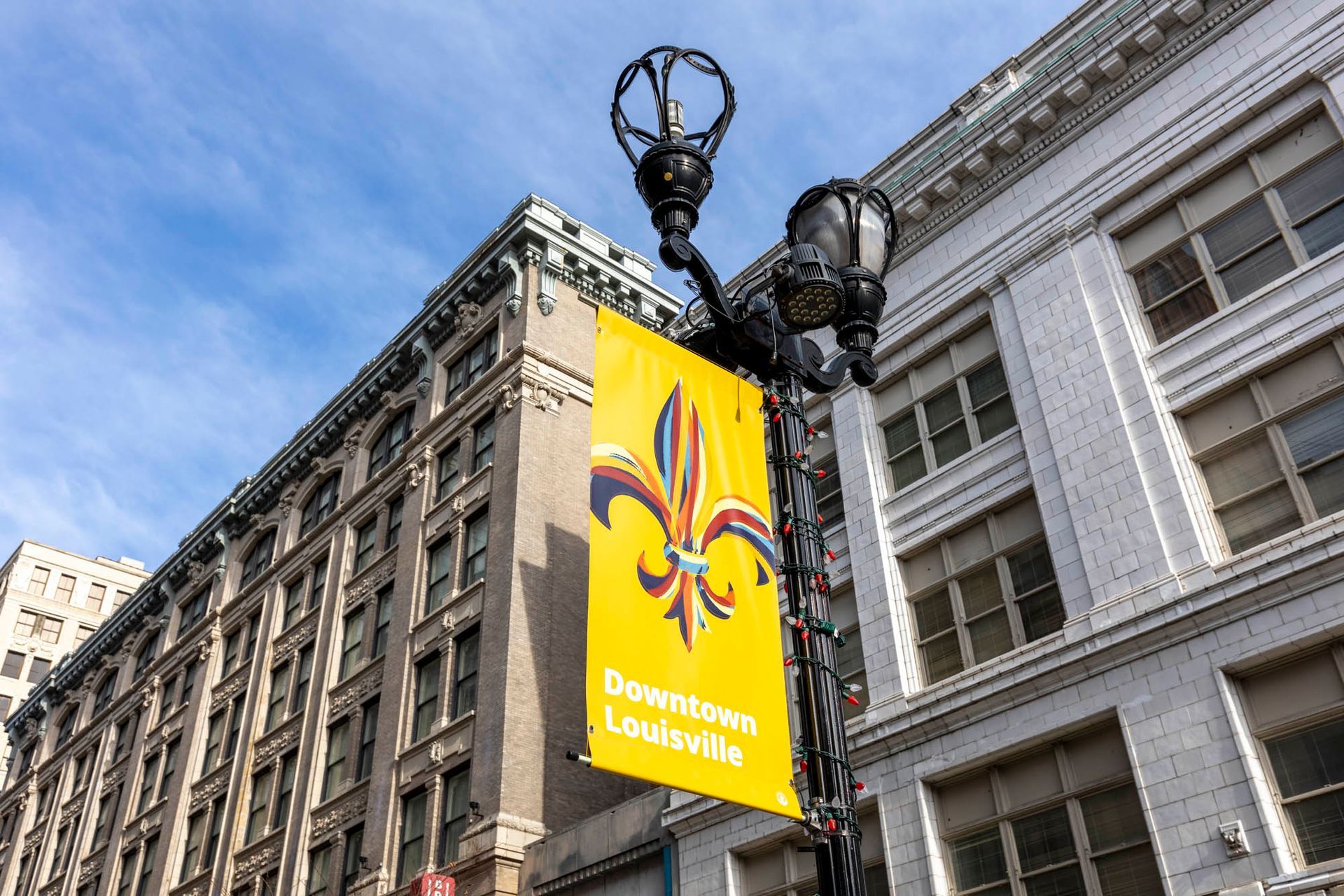 a yellow banner is hanging from a street light in front of a building .