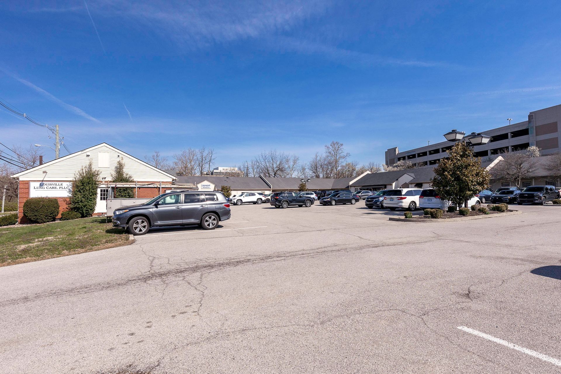 A lot of cars are parked in a parking lot in front of a building.