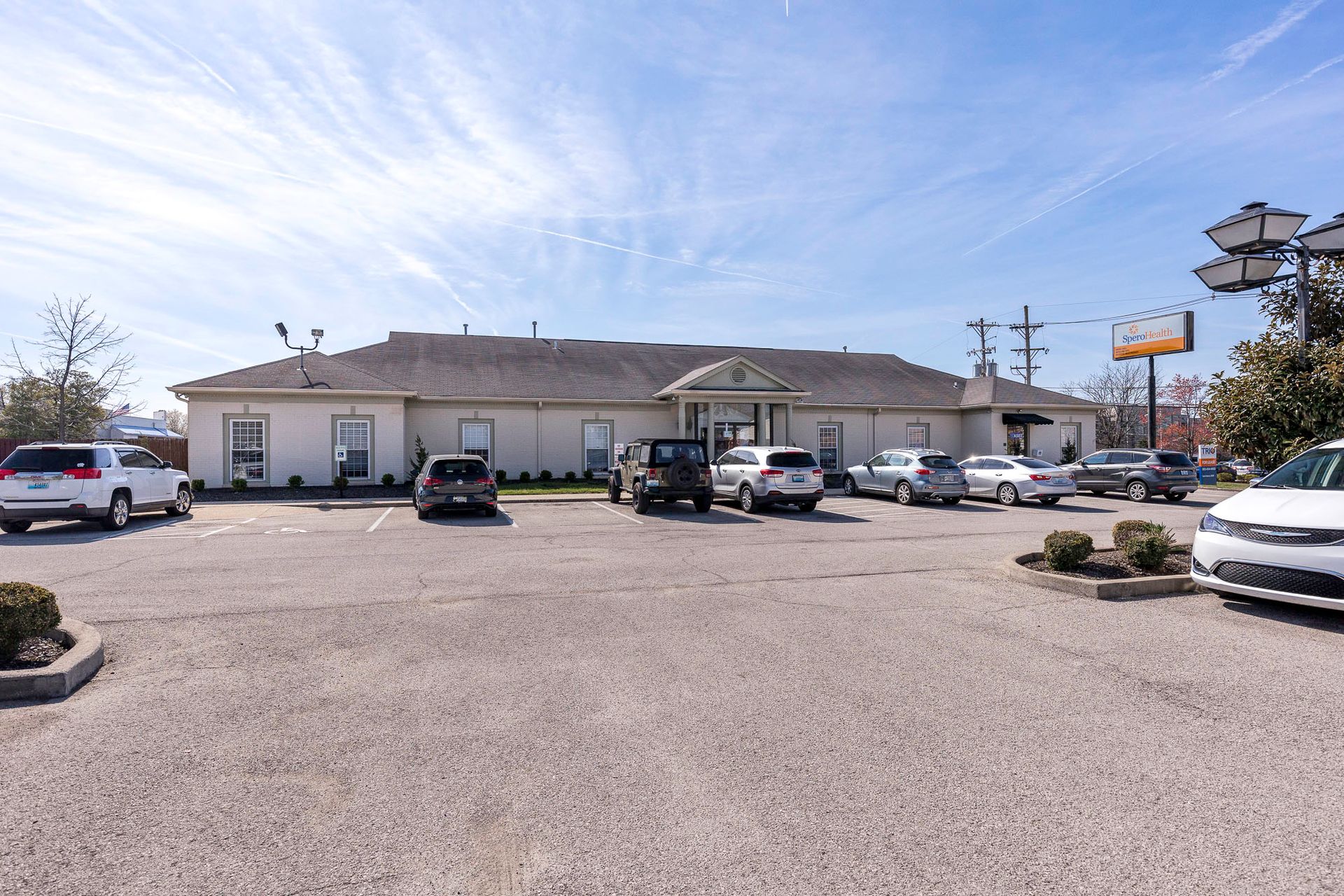 A lot of cars are parked in a parking lot in front of a building.