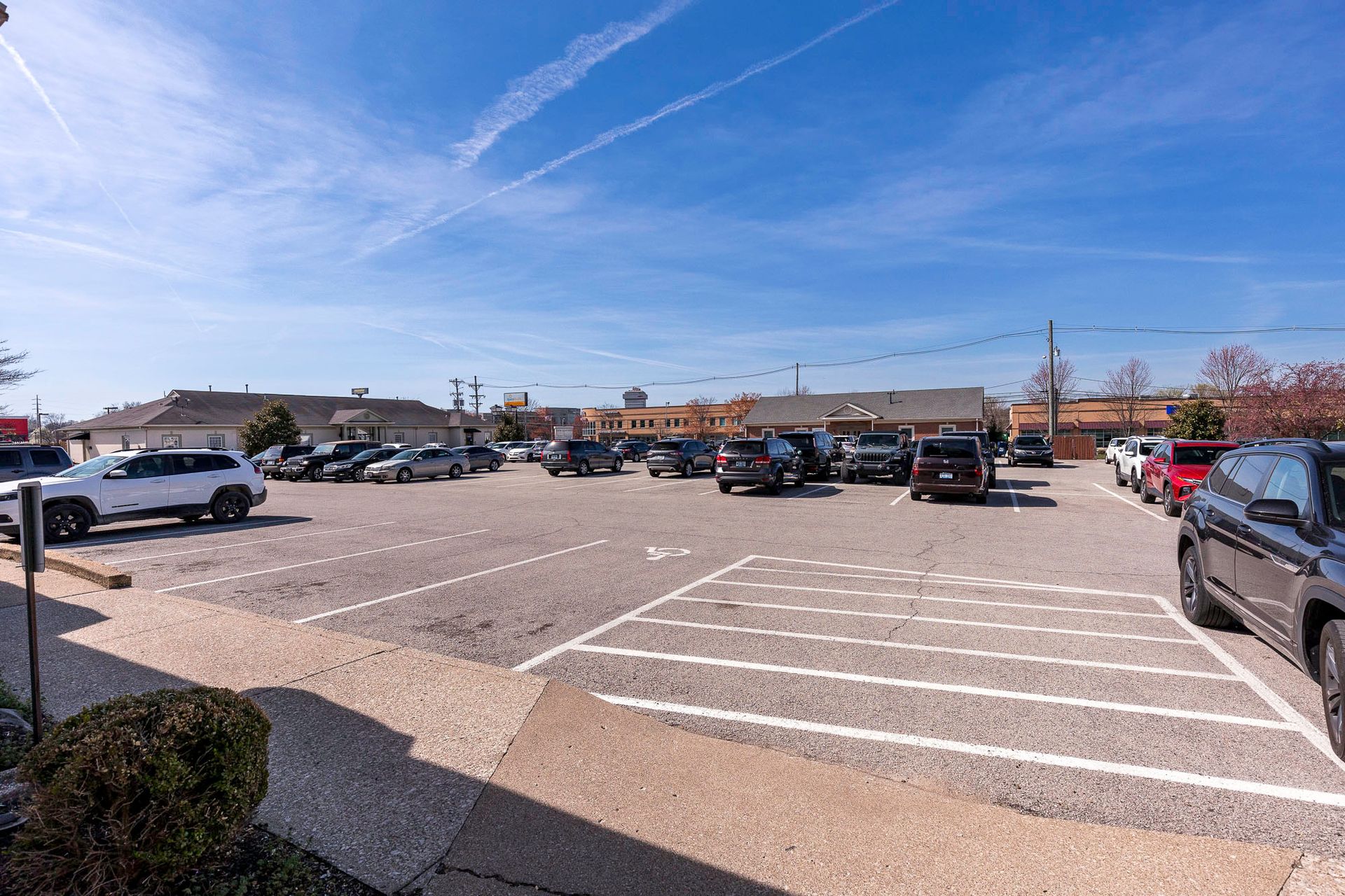 A lot of cars are parked in a parking lot in front of a building.