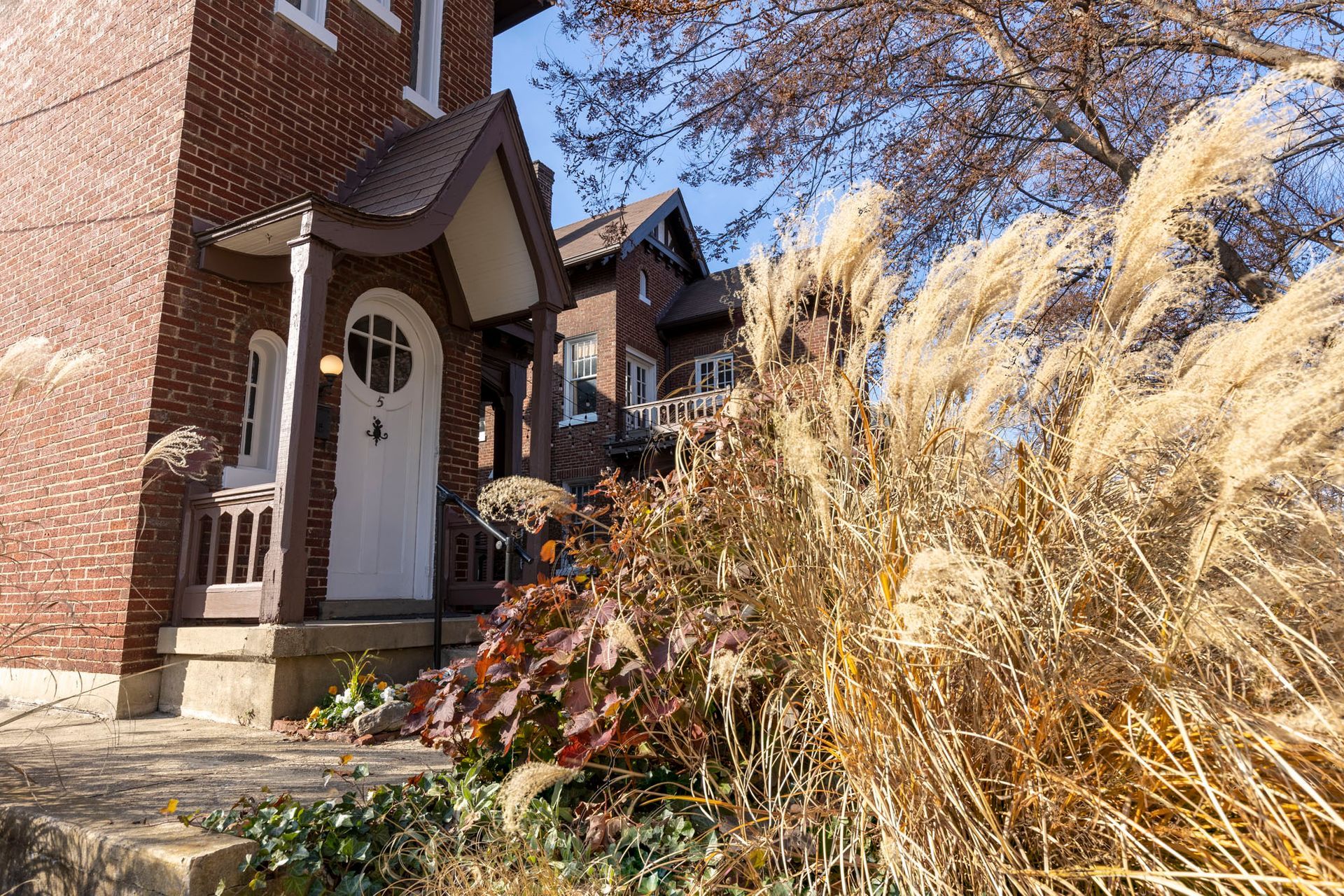 a brick house with a white door is surrounded by tall grass .