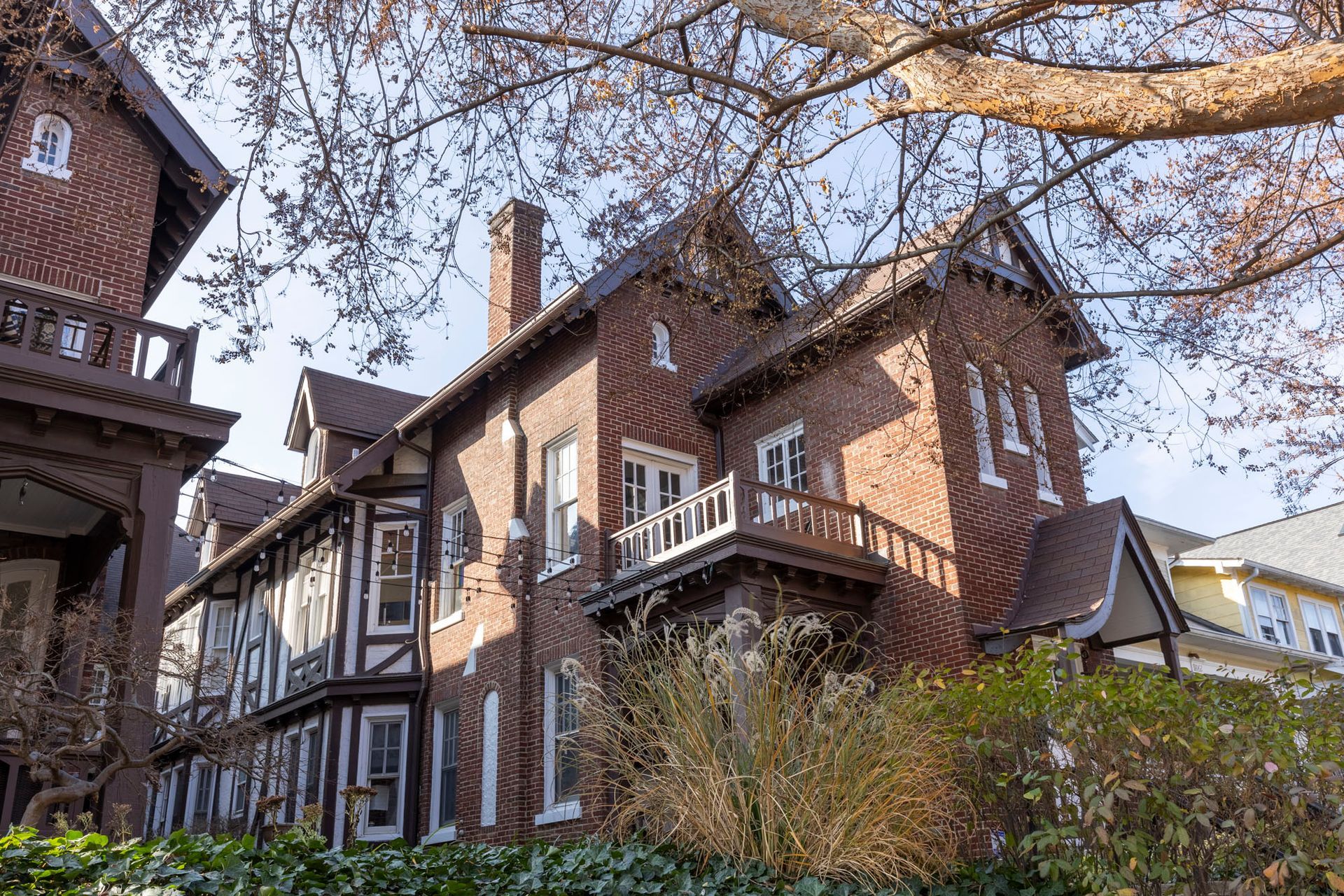 a large brick house with a balcony and a tree in front of it .