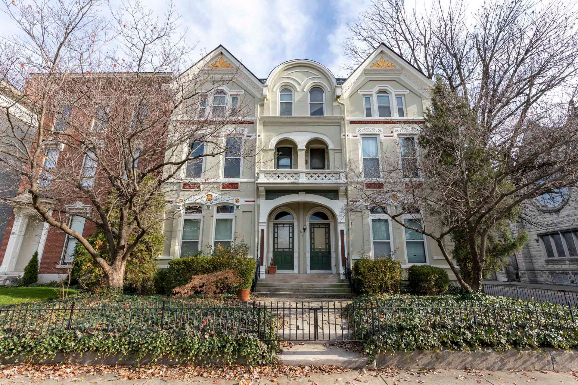 A large white building with a fence around it and trees in front of it.