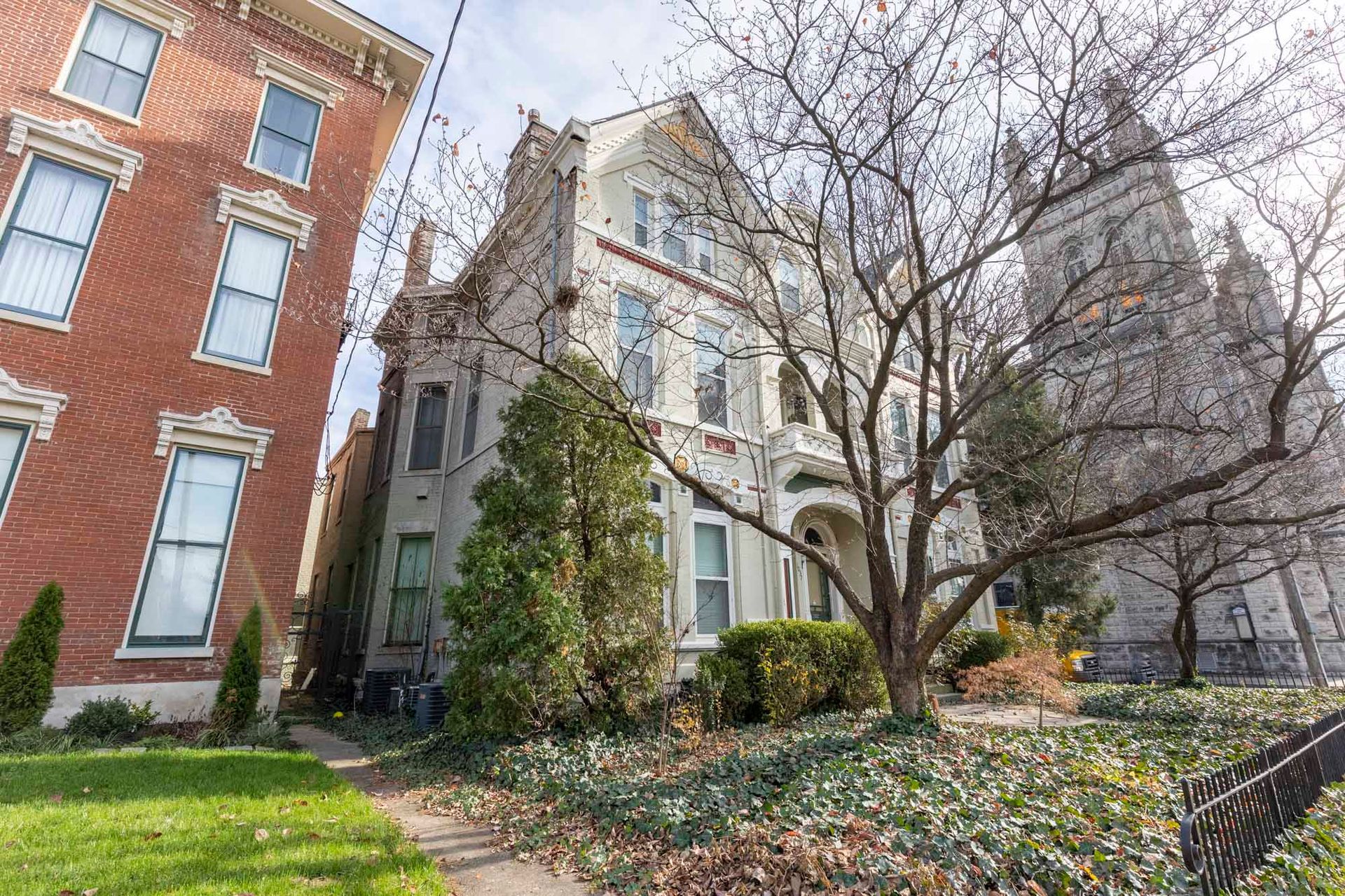 A large brick building with a lot of windows is next to a smaller building.