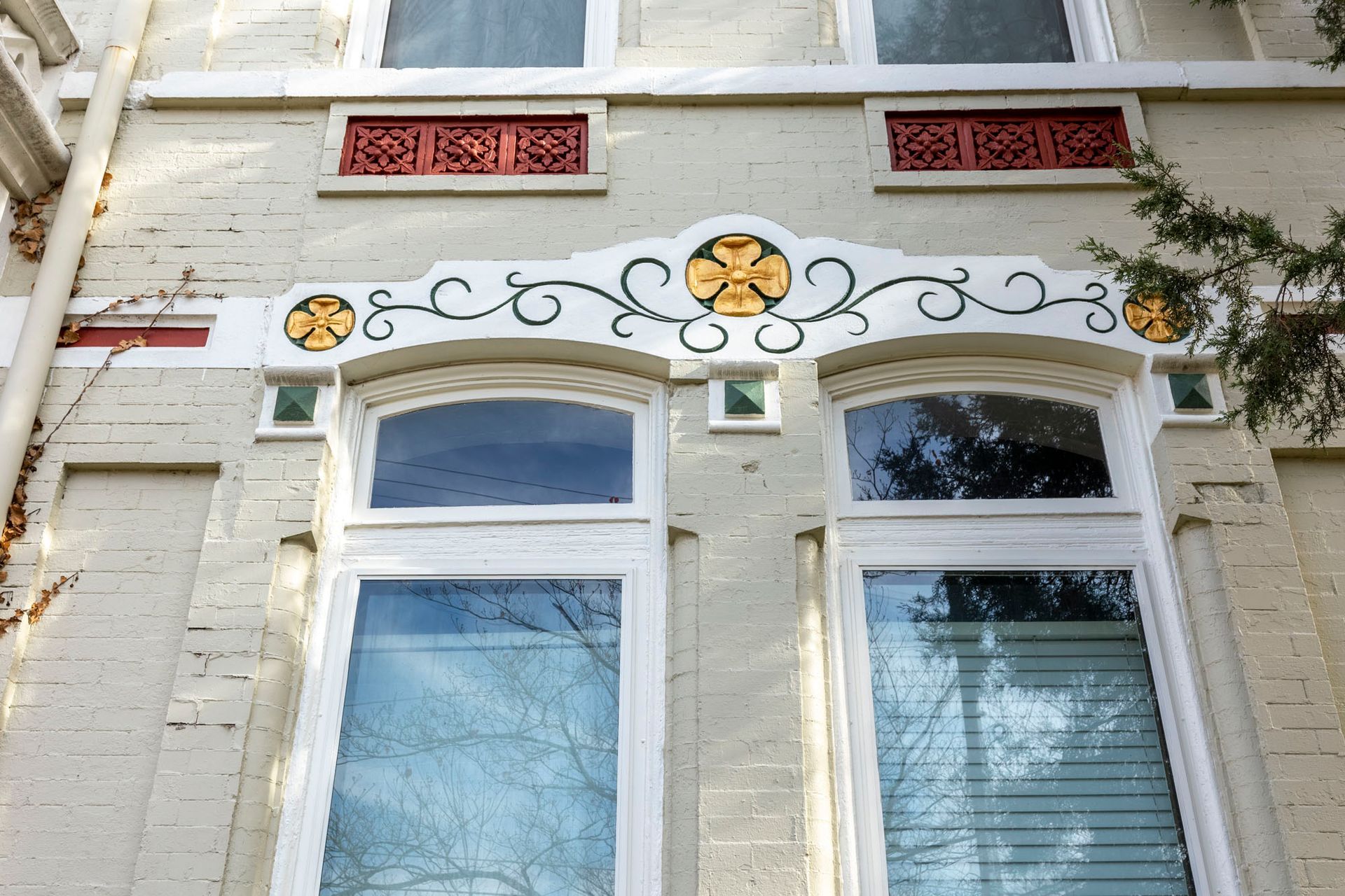 A white brick building with a window and a floral design on it