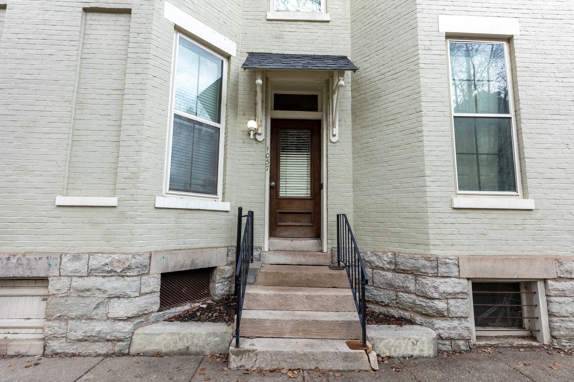 A white brick building with stairs leading up to the front door