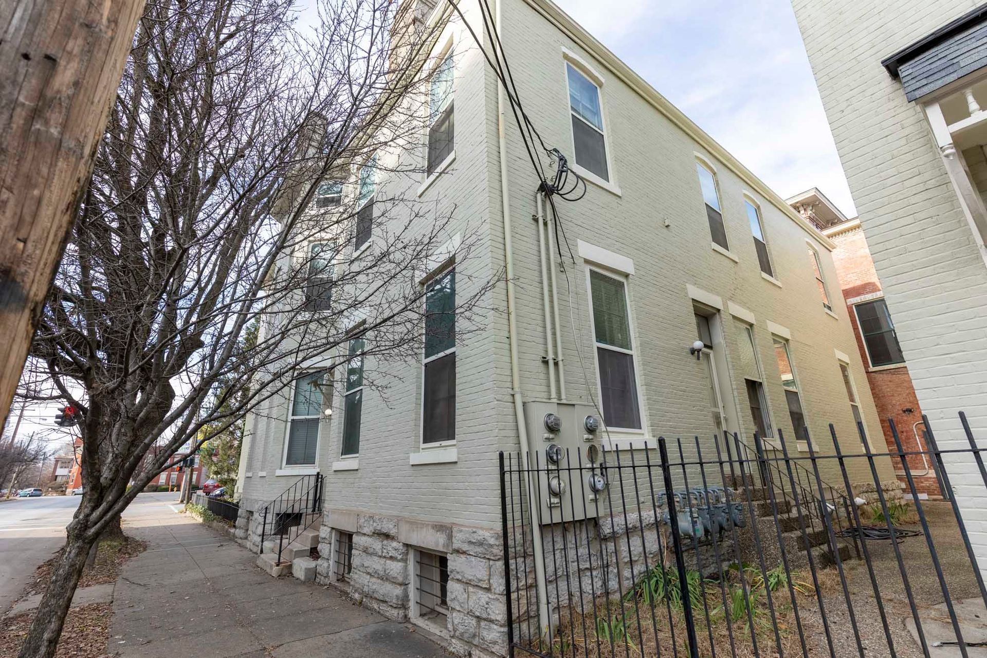 A white brick building with a wrought iron fence in front of it.