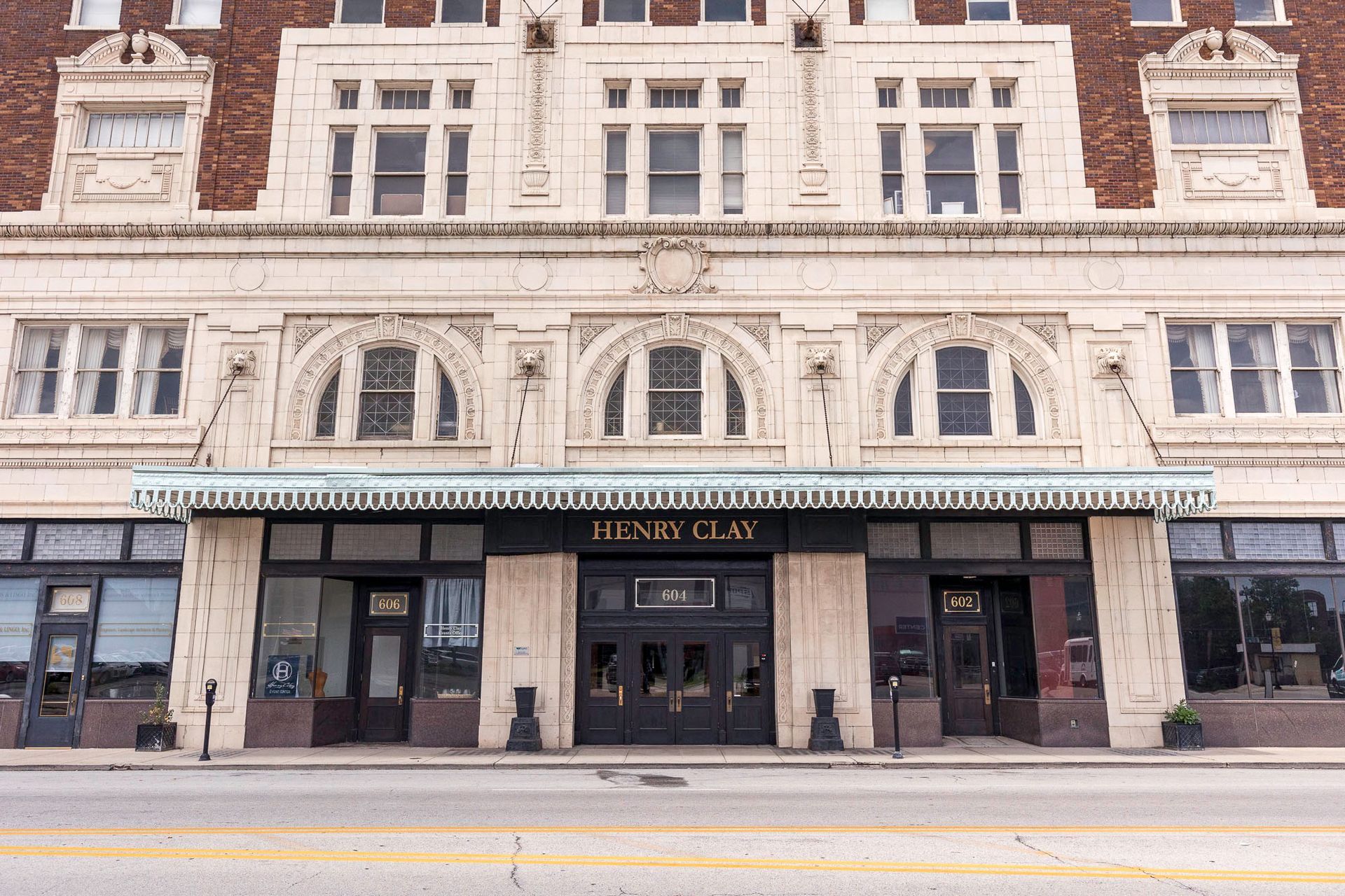 A large building with a lot of windows and doors is on the side of the road.