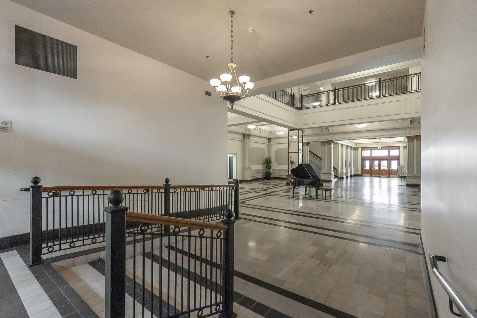 A large hallway with stairs and a piano in the middle