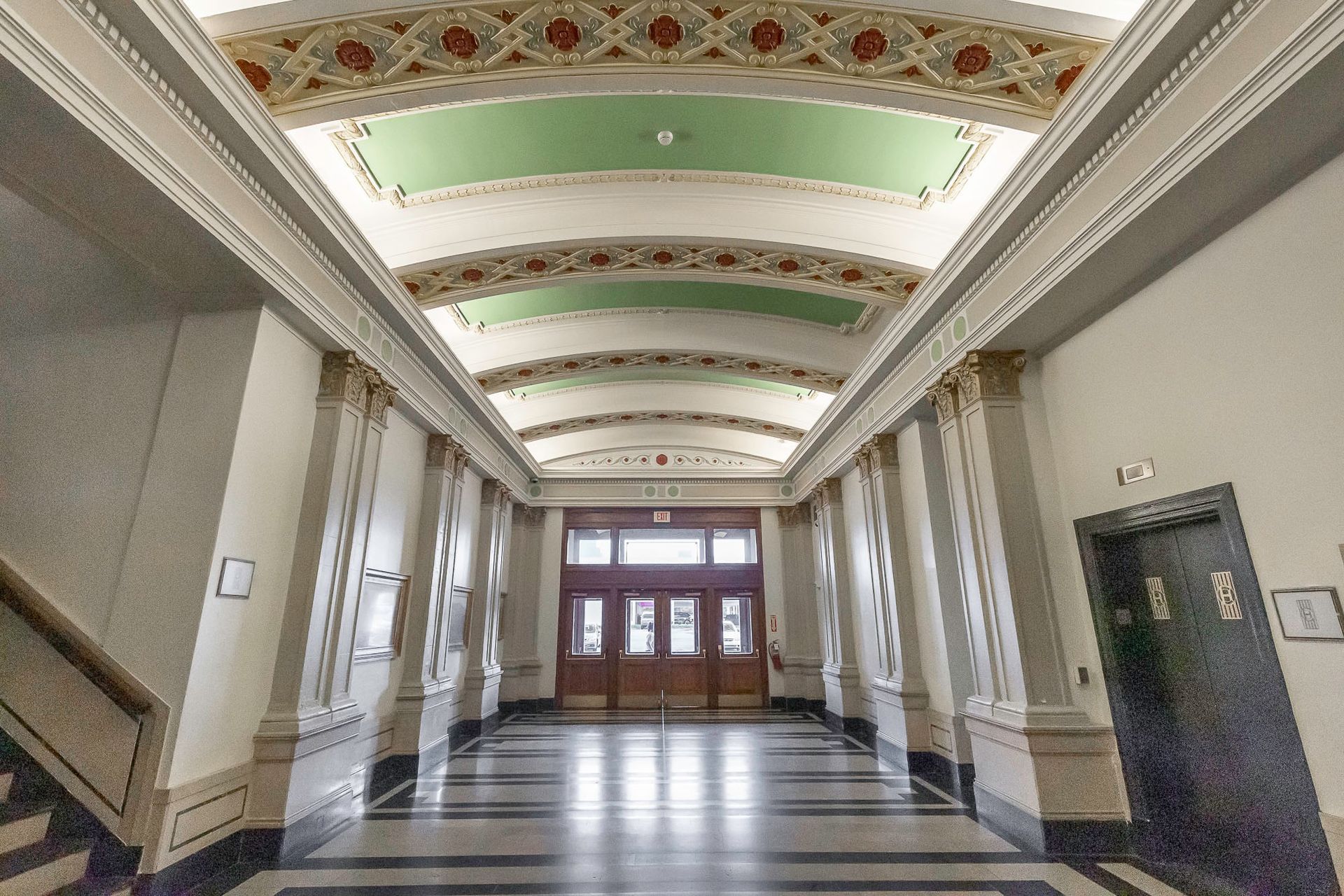 A long hallway in a building with a green ceiling