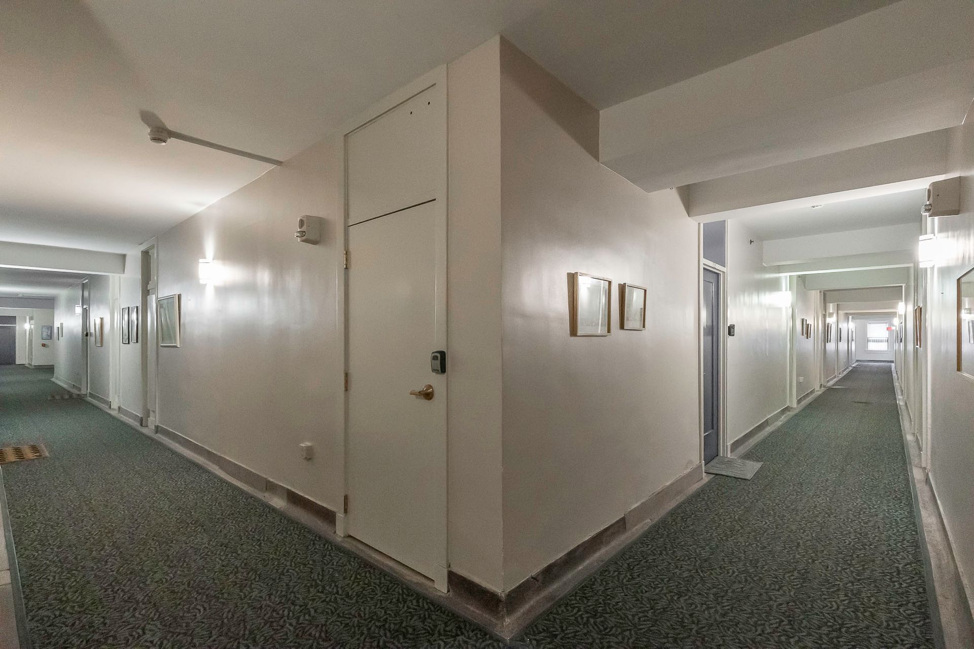 A long hallway with a green carpet and white walls.