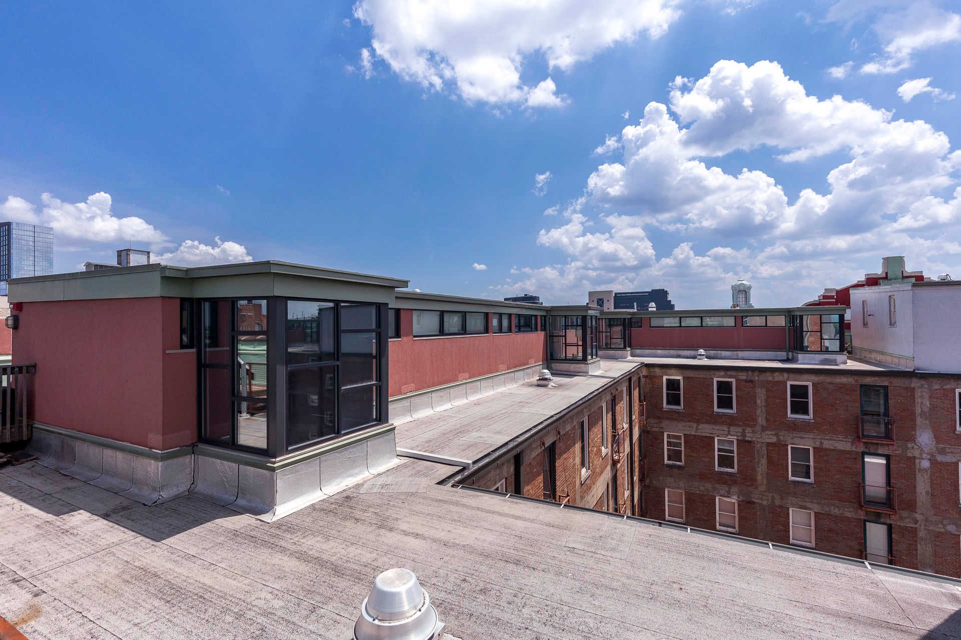 A rooftop view of a brick building with a blue sky and clouds in the background.