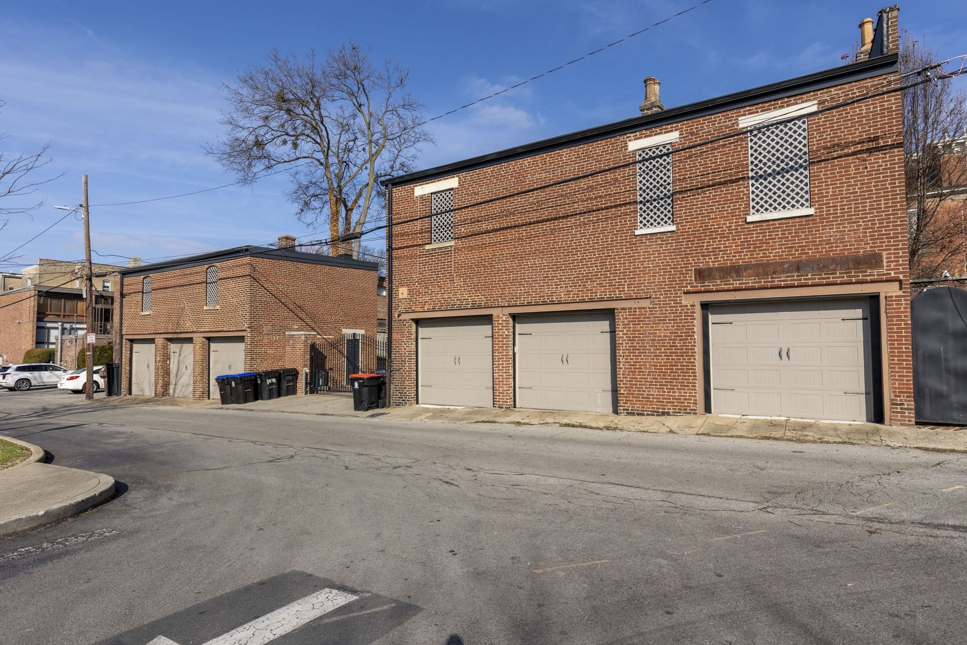 a row of brick buildings with garages on the side of the road .