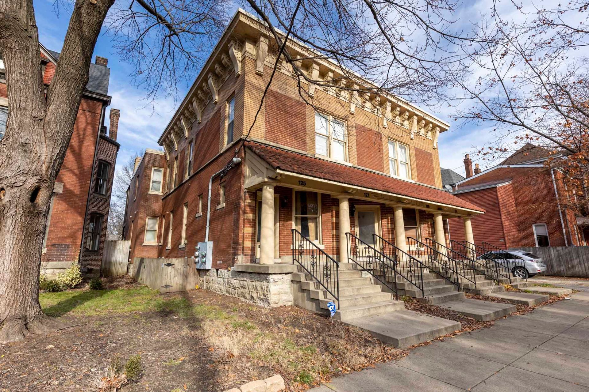 a large brick building with a porch and stairs in front of it .