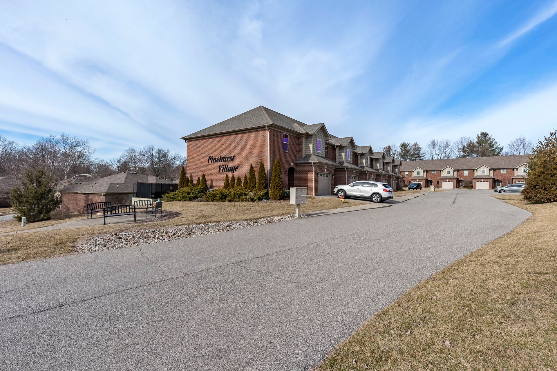 A large brick apartment building with a lot of cars parked in front of it.