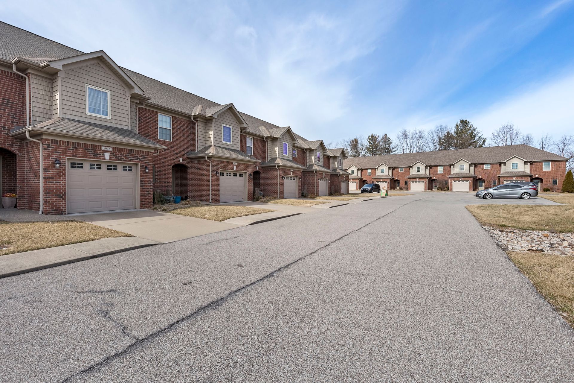 A row of apartment buildings with cars parked in front of them.