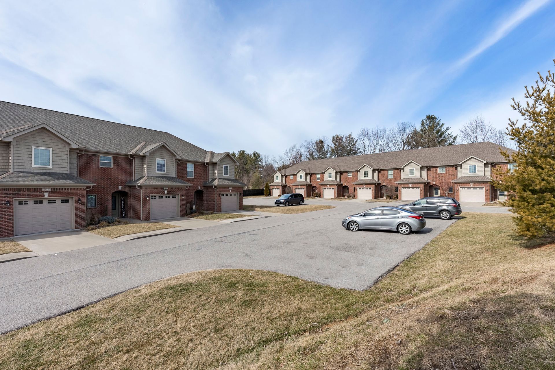A row of houses with cars parked in front of them on a sunny day.