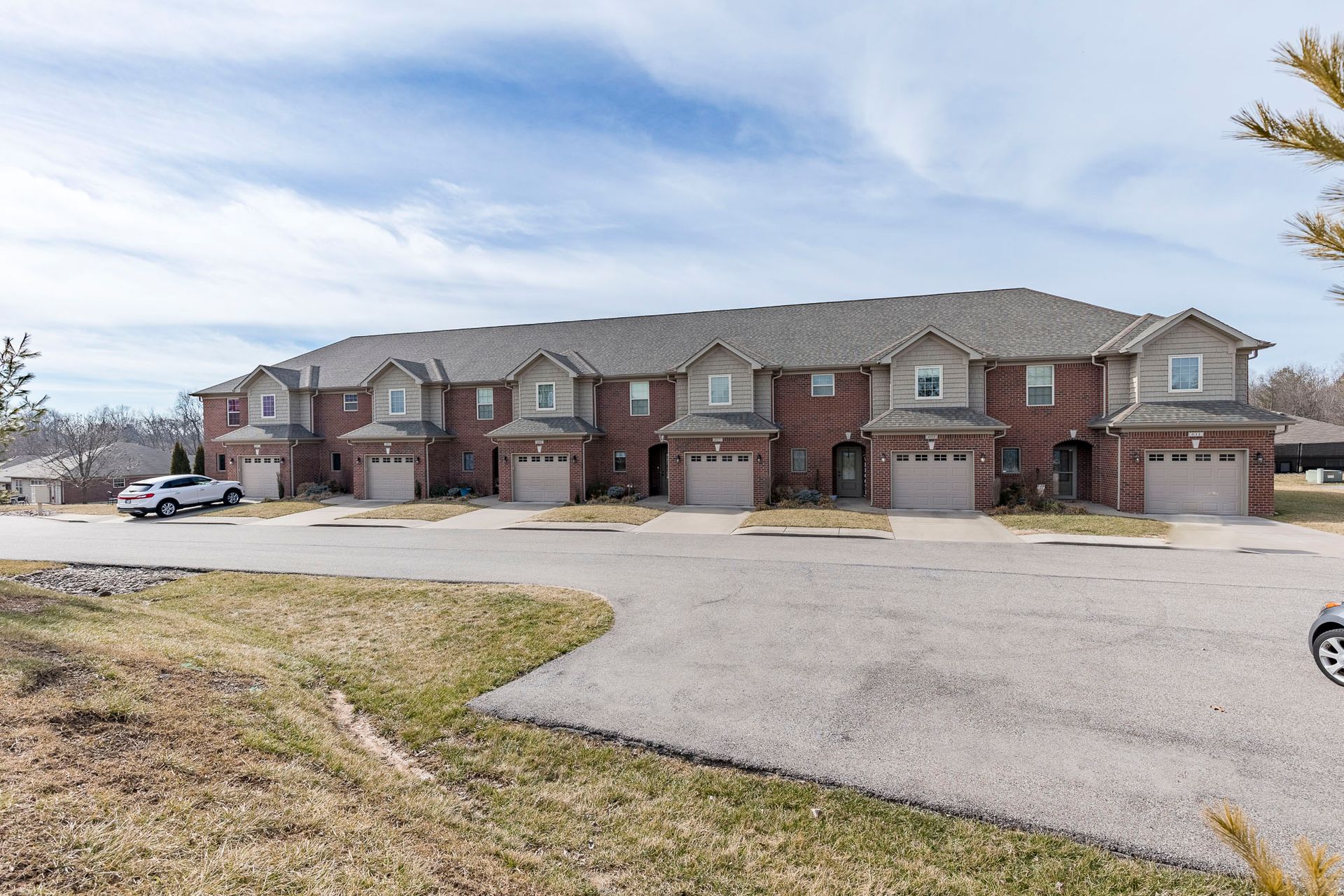 A row of apartment buildings with cars parked in front of them.