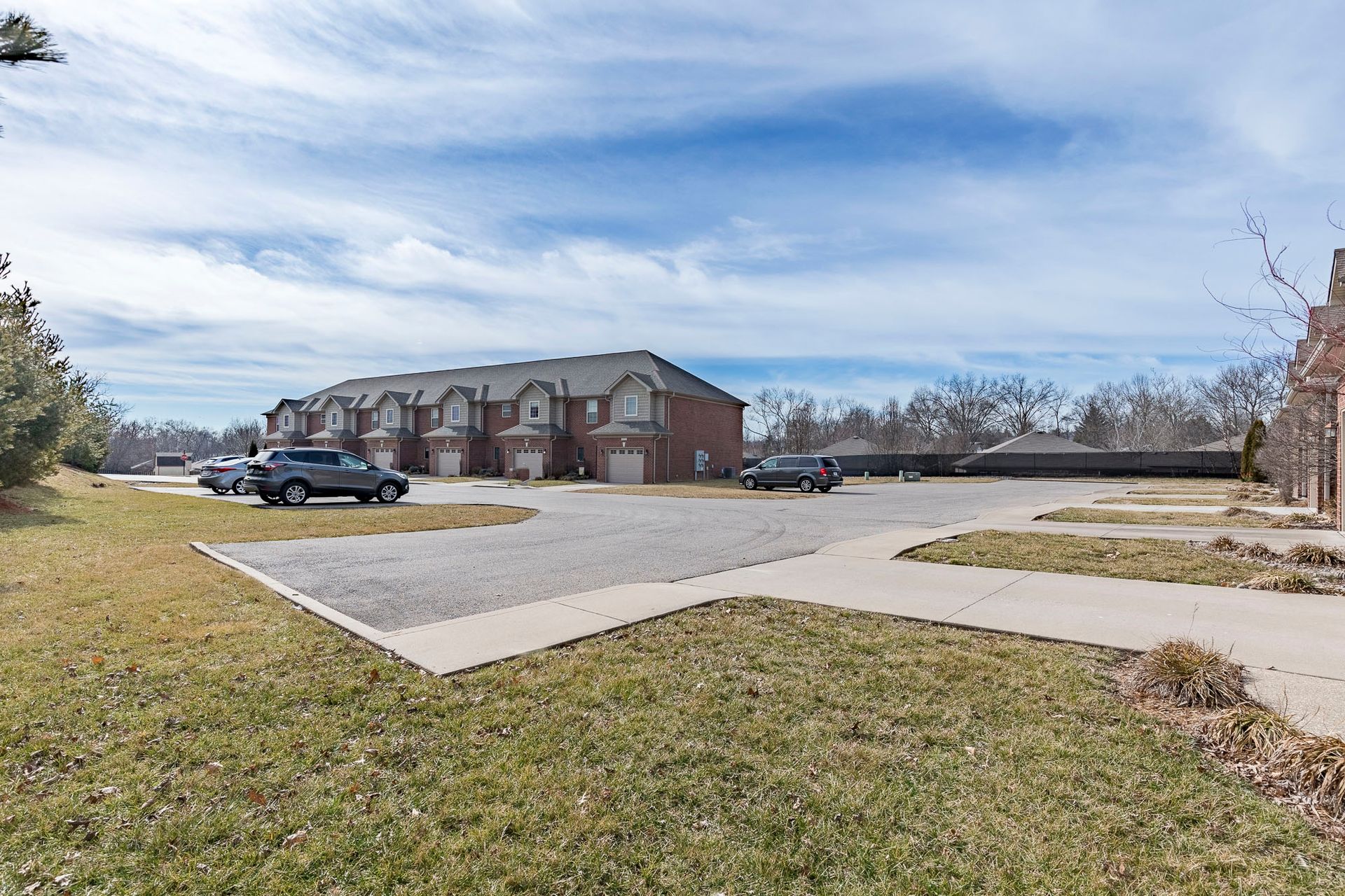 A parking lot with cars parked in front of a row of houses.