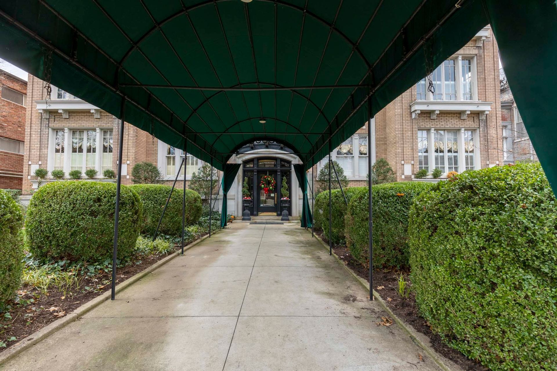 a green canopy over a driveway leading to a building .