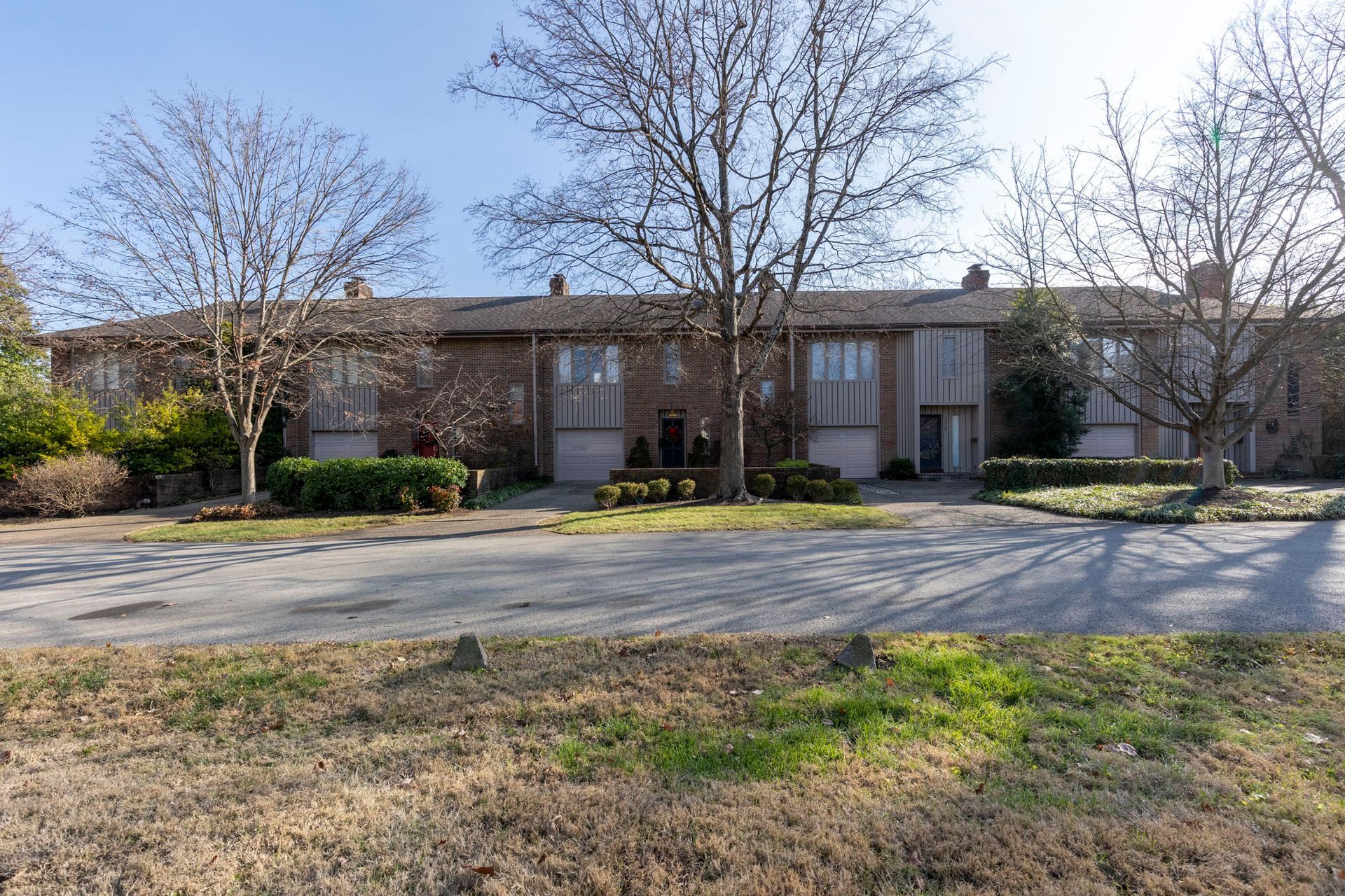 A row of houses with trees in front of them on a sunny day.