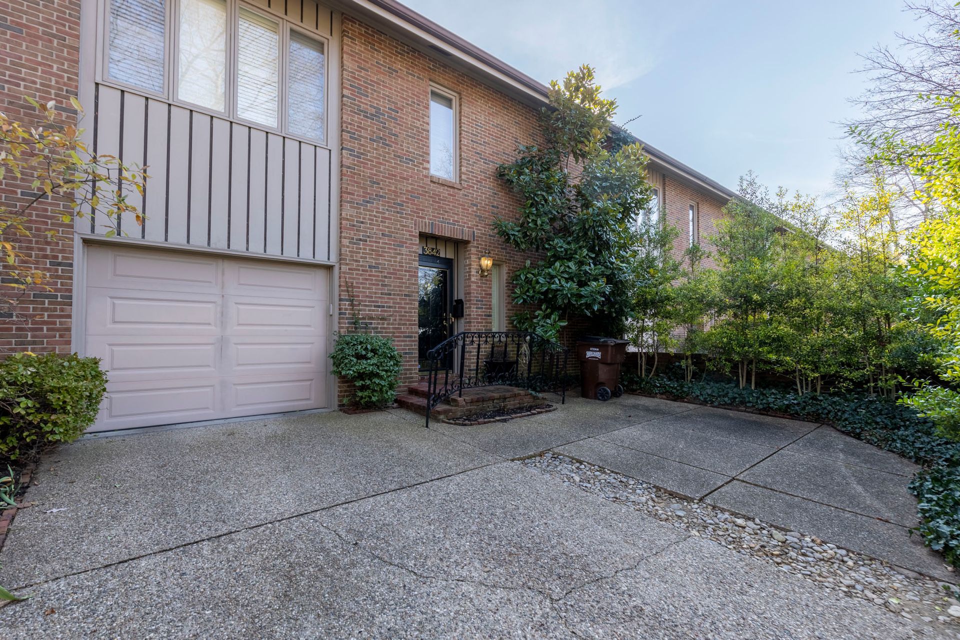 A brick house with a garage and a driveway in front of it.