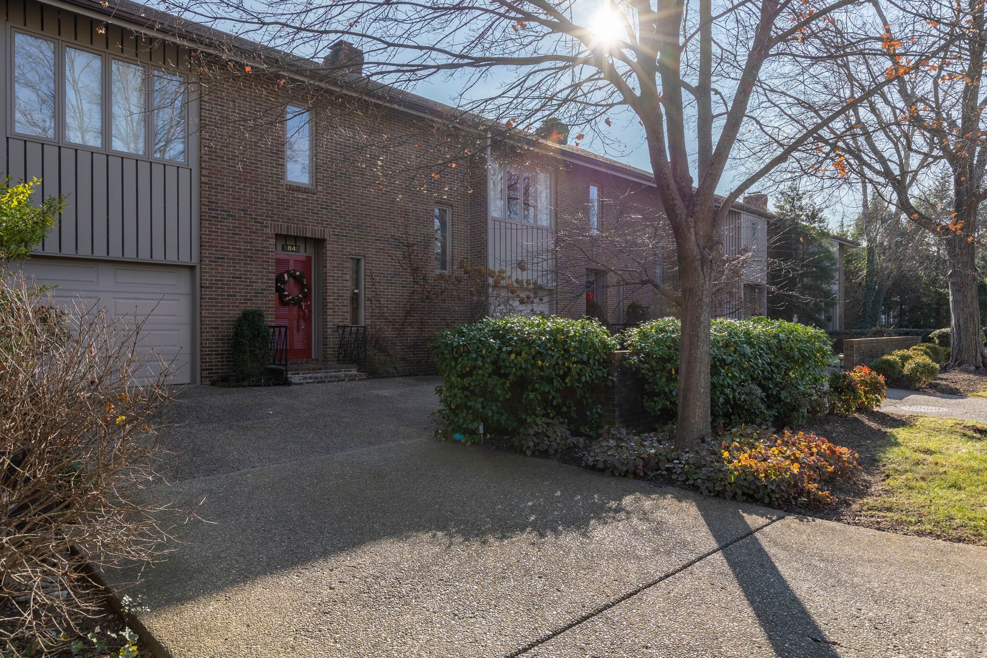 A brick house with a red door and a tree in front of it.