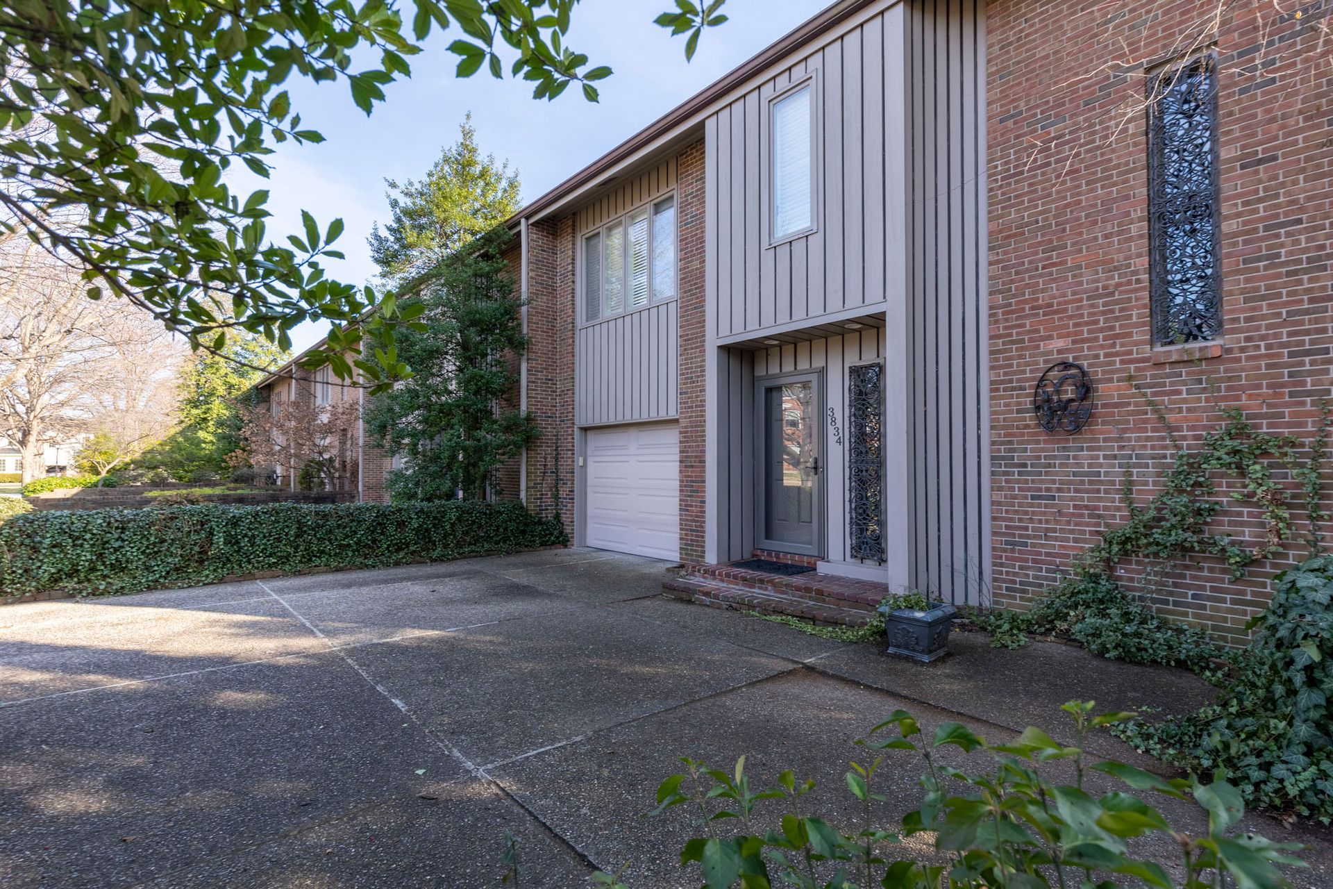 A brick house with a garage and a driveway in front of it.