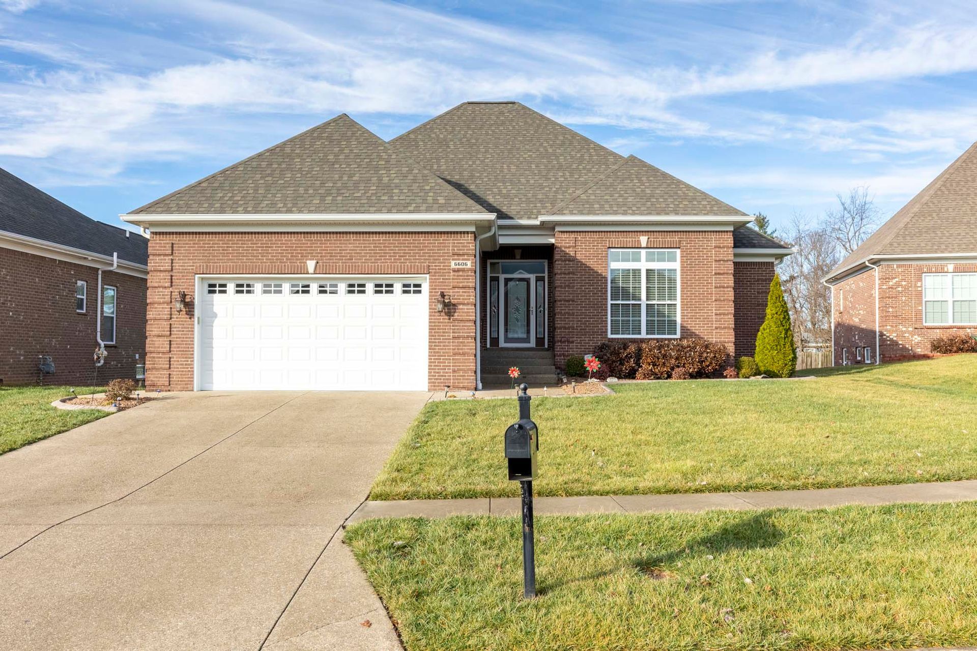 a brick house with a white garage door and a mailbox in front of it .
