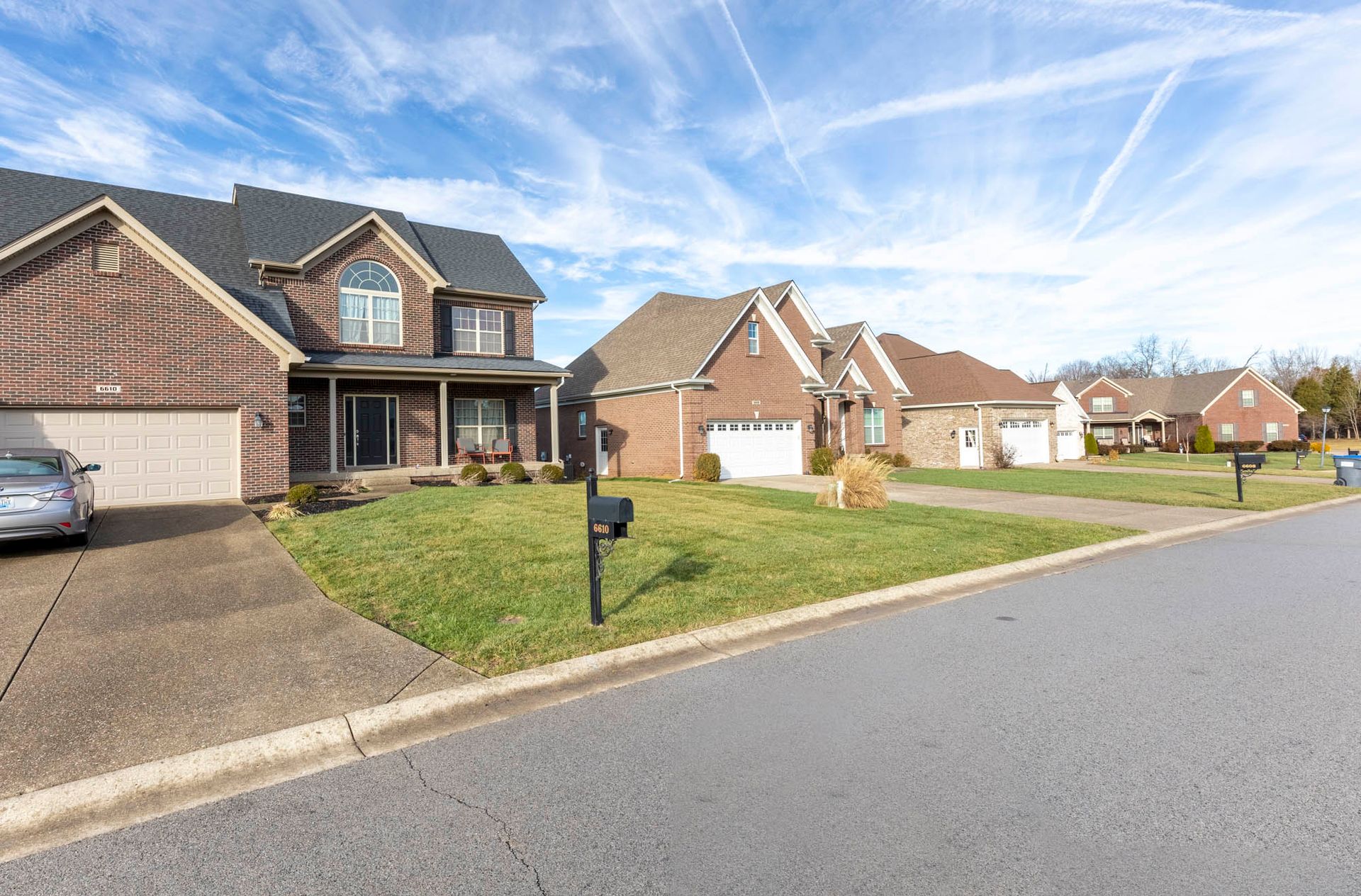 a car is parked in front of a brick house in a residential neighborhood .