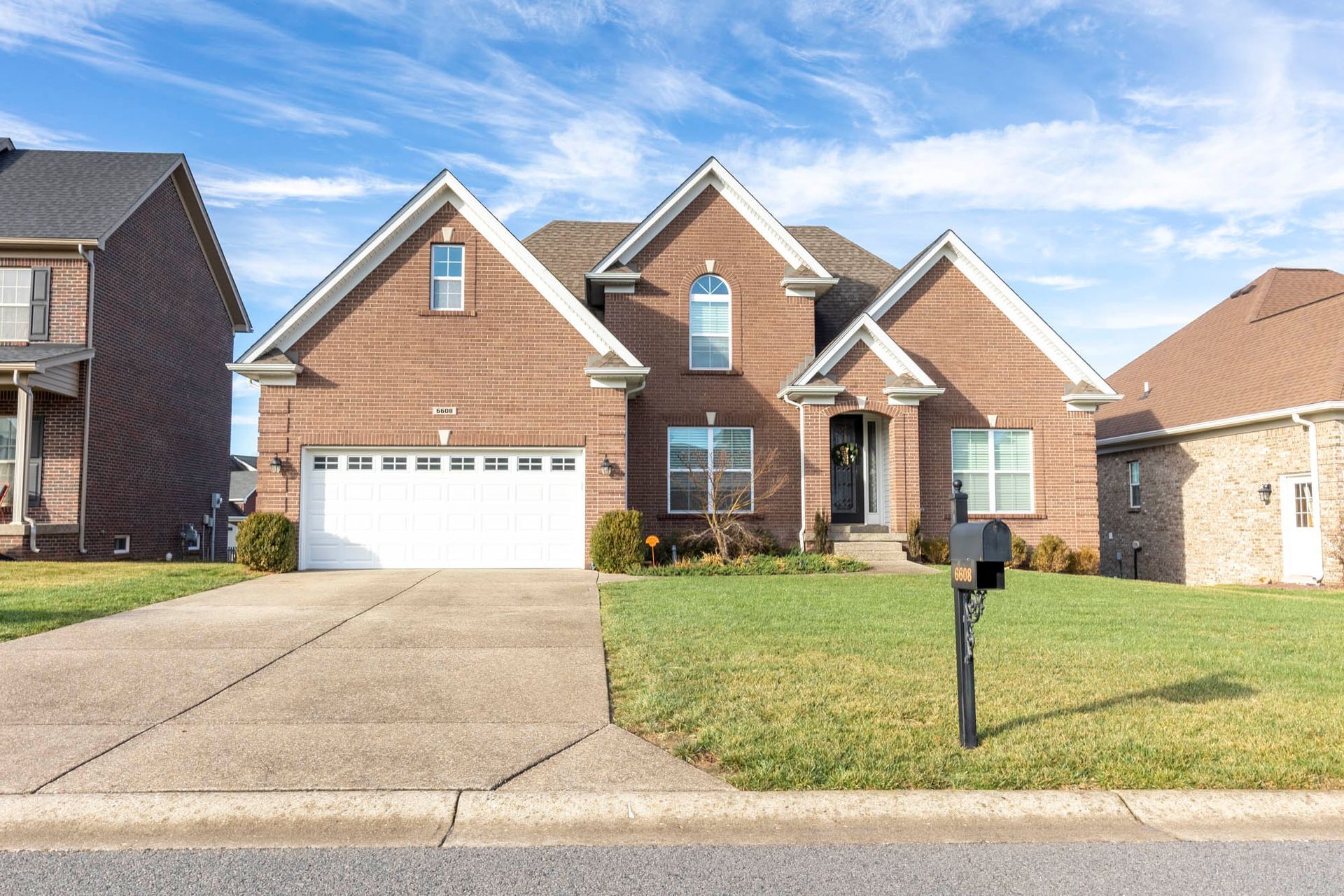 a large brick house with a white garage door and a mailbox in front of it .