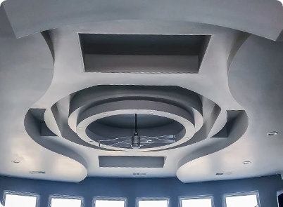 Ornate gray ceiling with circular and rectangular recessed areas, a ceiling fan hangs in the center.