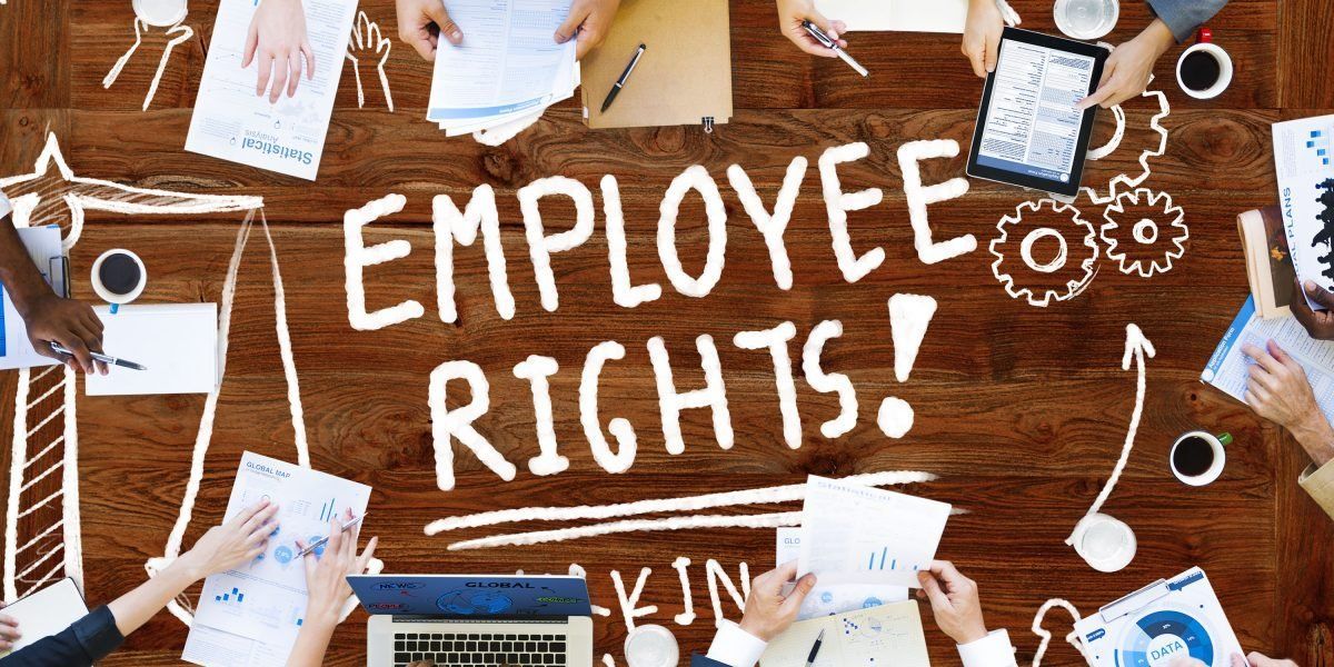 A group of people are sitting around a table with the words `` employee rights '' written on it.