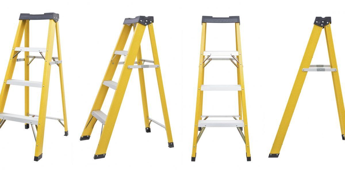 A group of yellow ladders sitting next to each other on a white background.