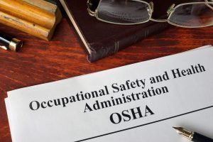 A piece of paper that says occupational safety and health administration osha on a wooden table.