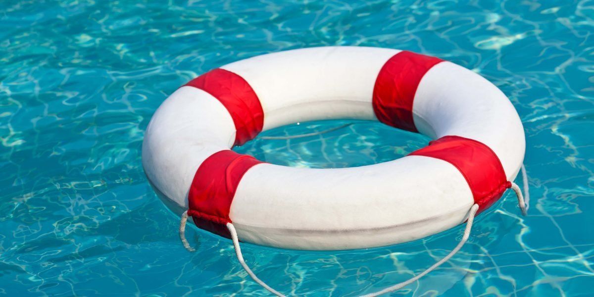 A red and white life preserver is floating in a swimming pool.