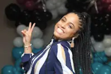 A woman is giving a peace sign in front of balloons.