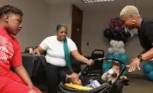 A group of people are sitting around a stroller with a baby in it.