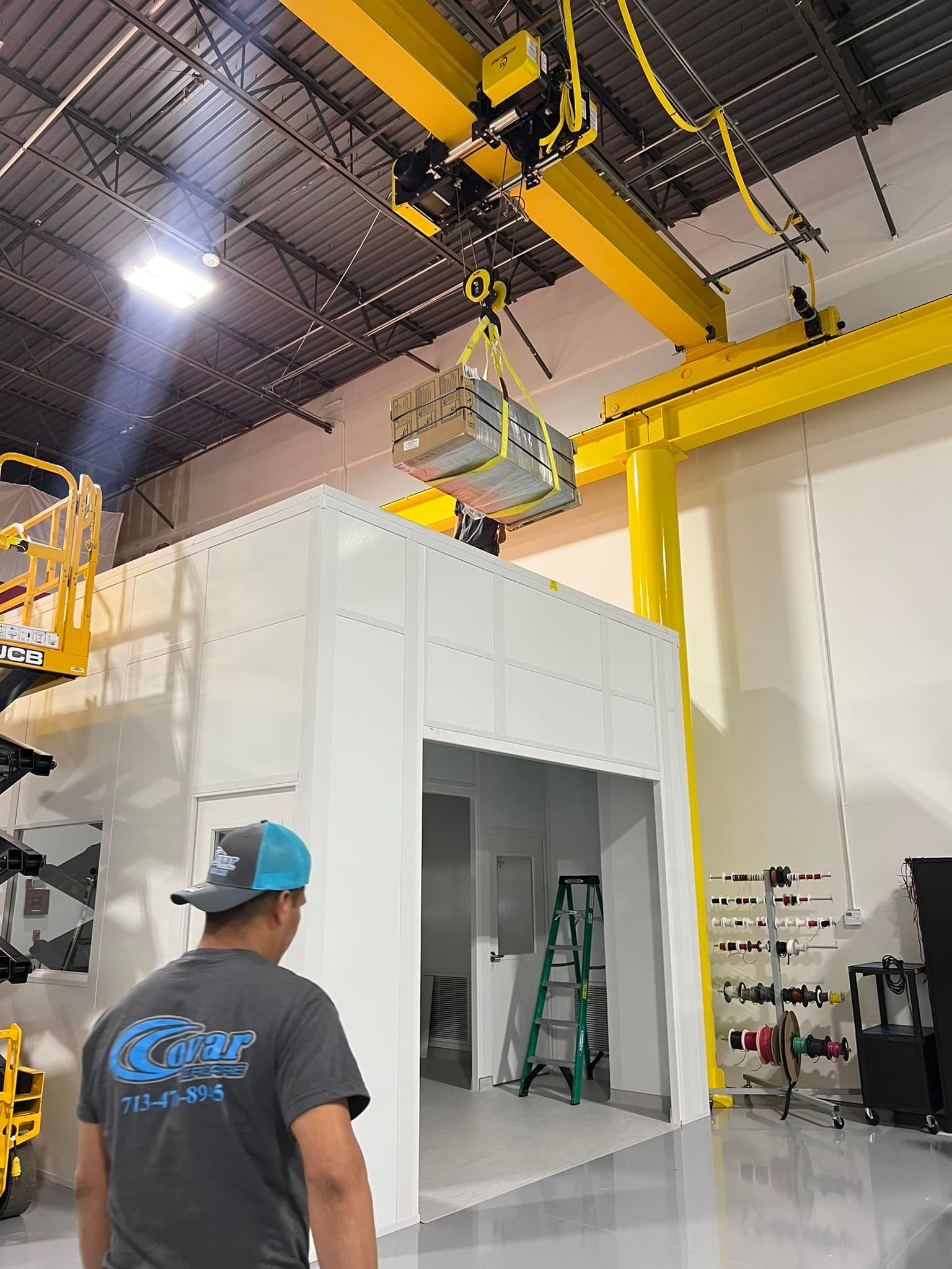 A man is standing in front of a crane in a factory.