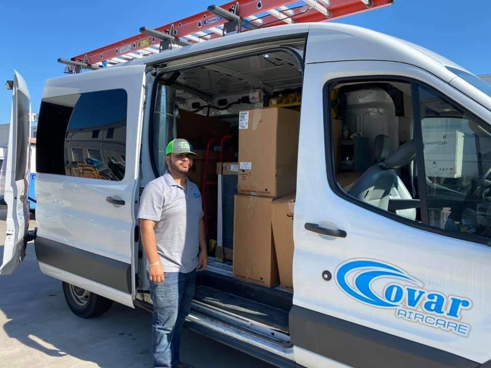 A man is standing in front of a covar van.