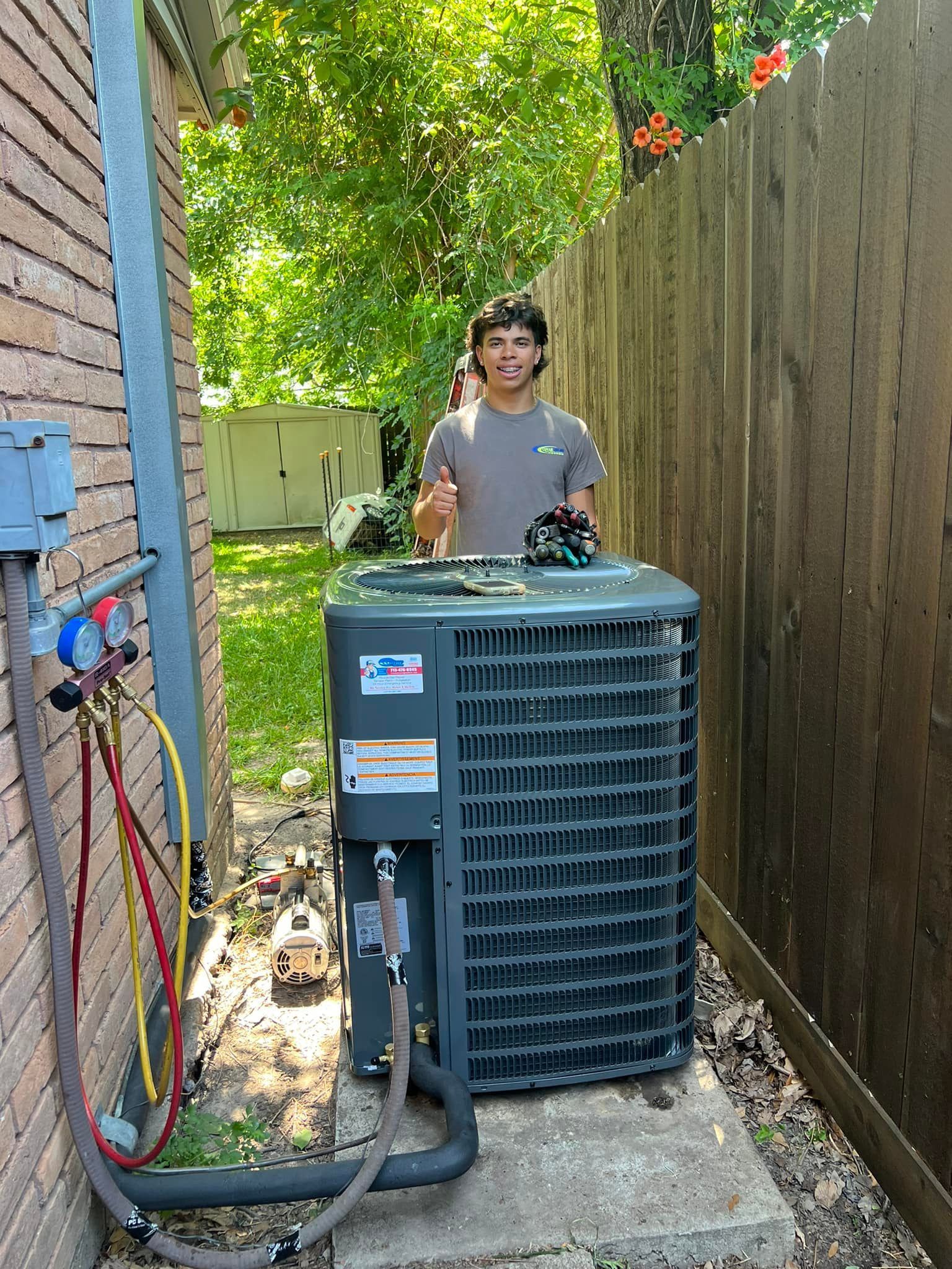 A man is standing next to an air conditioner in a backyard.