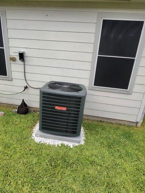 An air conditioner is sitting on the side of a house.